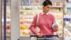 Eine Frau kauft im Supermarkt ein und liest das Etikett auf einem Becher.